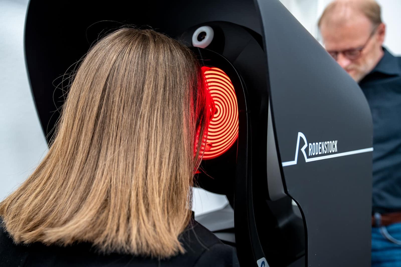 Kundin bei der Augenvermessung an einem Rodenstock-Messgerät mit rotem Ringlicht