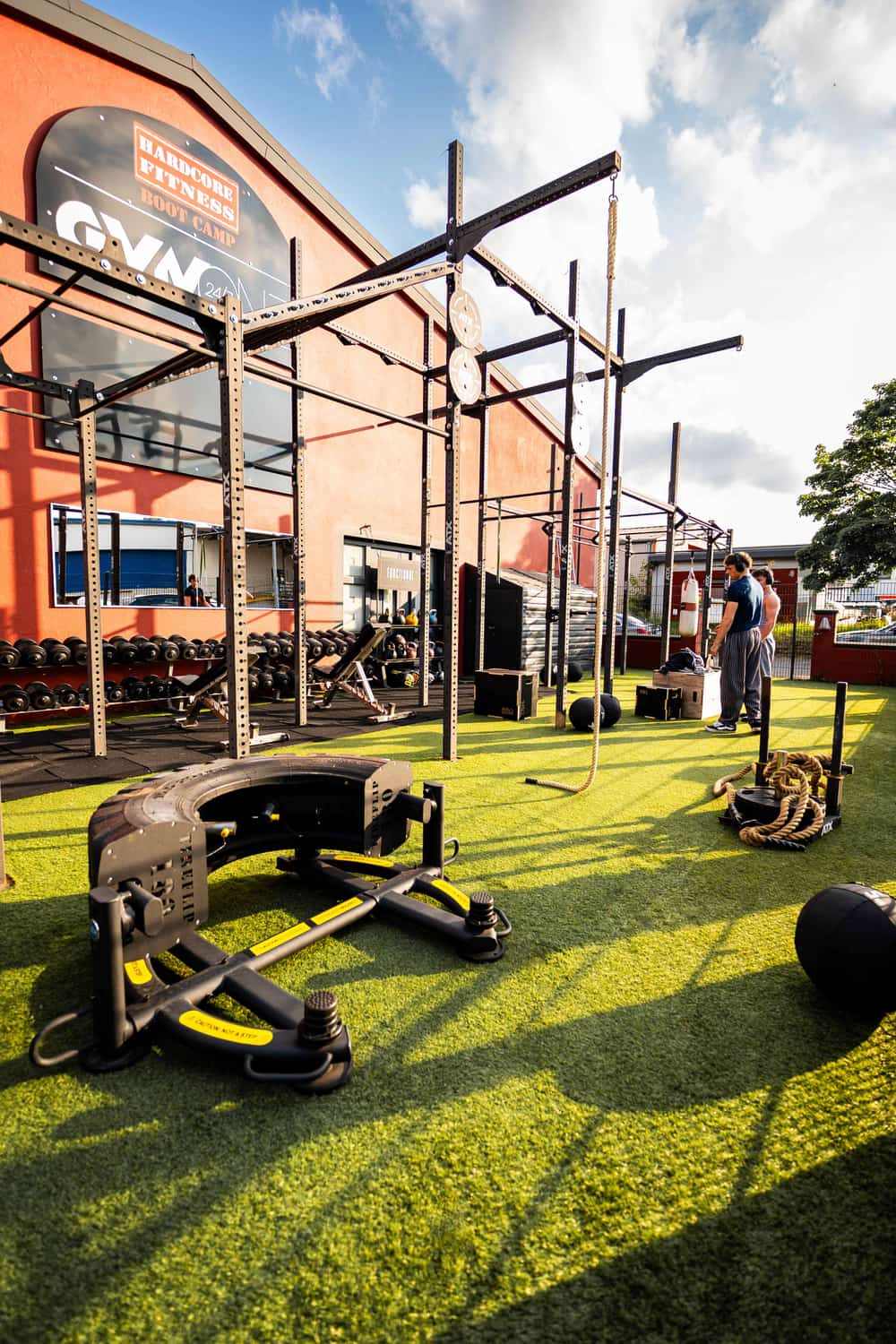 Outdoor-Functional-Training- und Bootcamp-Bereich des GymOne 24/7 Bitburg mit Rig, Prowler und Reifen auf Kunstrasen
