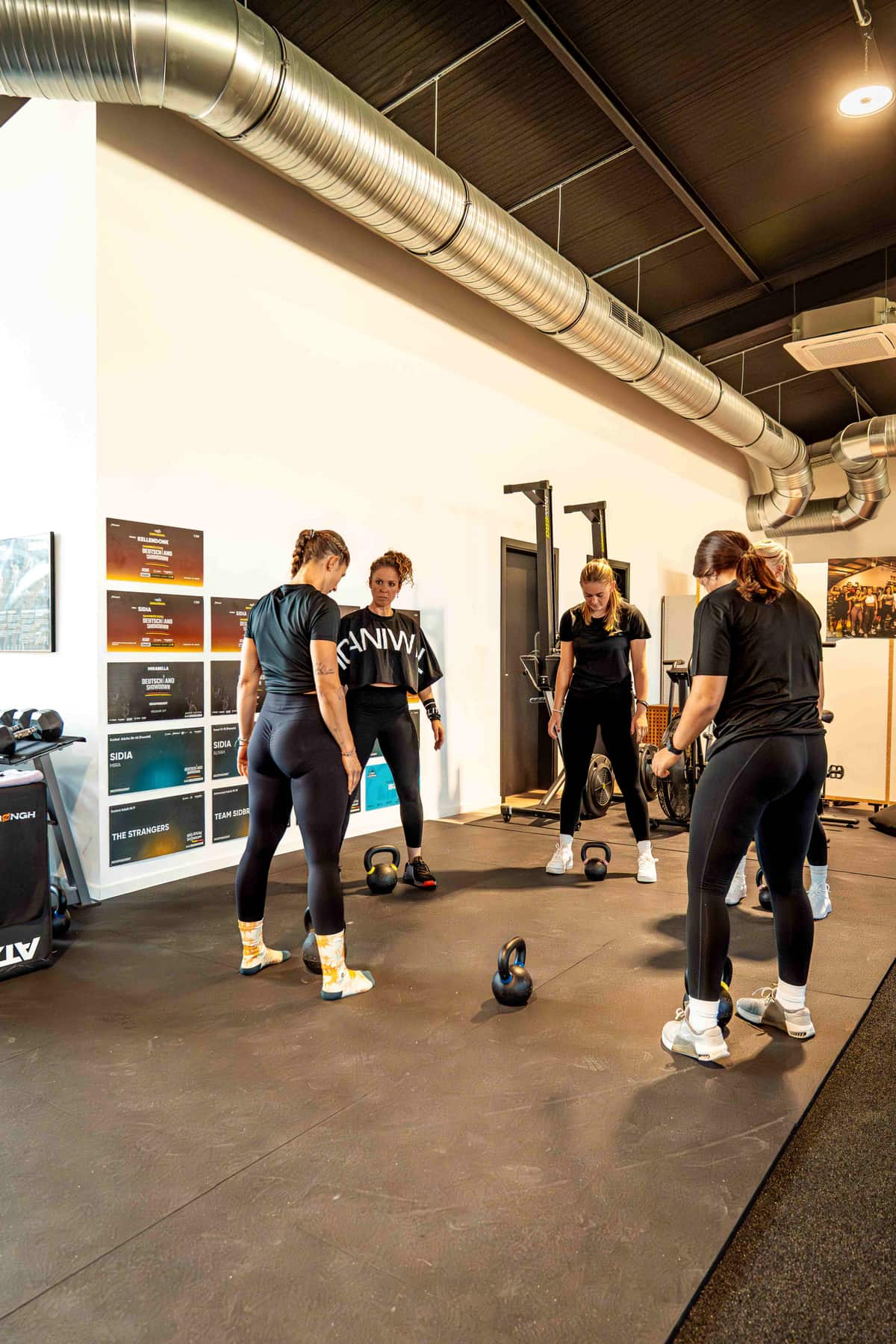 Gruppentraining mit Kettlebells im Strongh Fitnessstudio Temmels vor der Wand mit Wettkampf-Postern