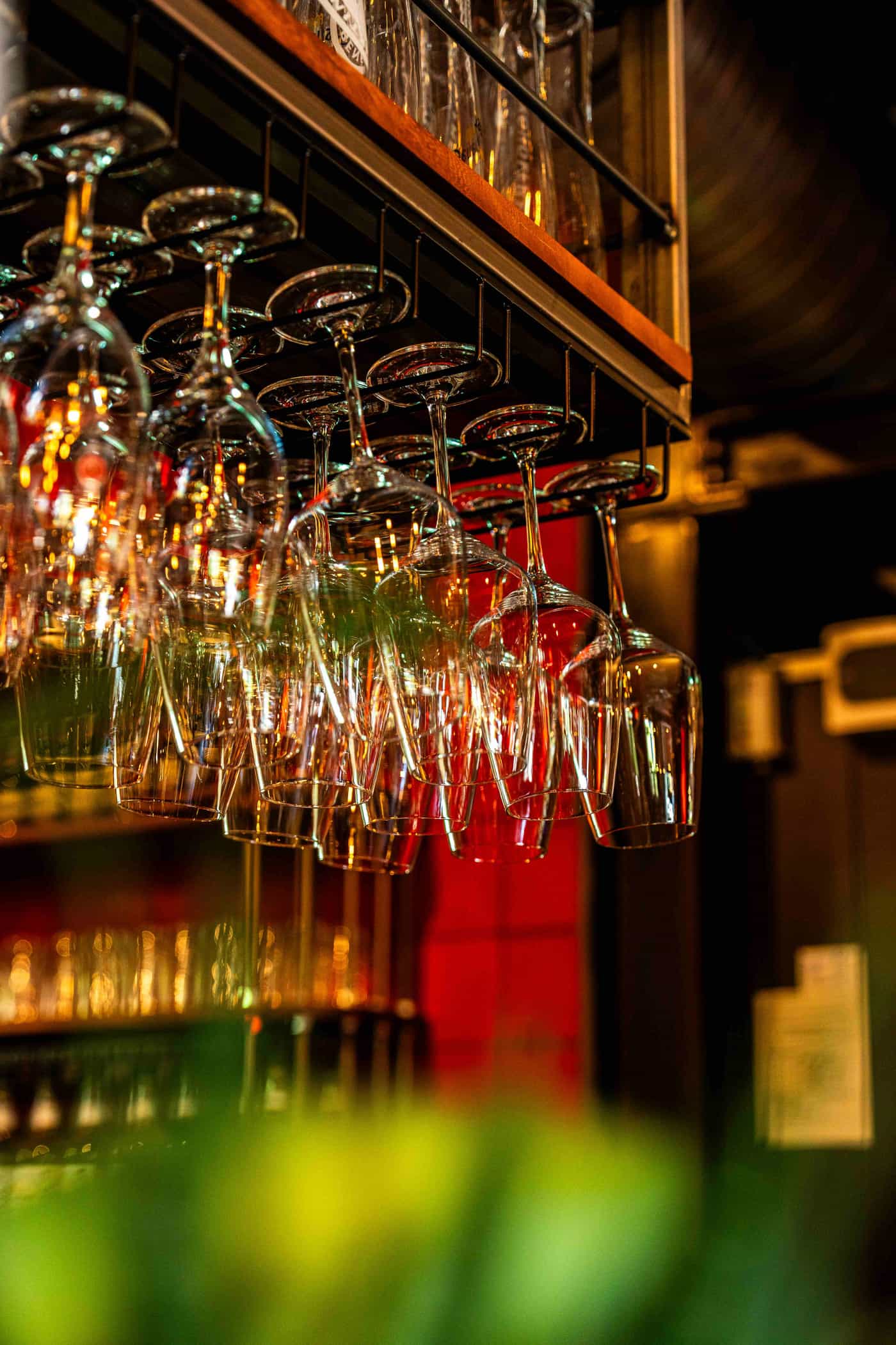 Kopfüber hängende Weingläser an der Bar des Wirtshaus Moers im warmen Licht
