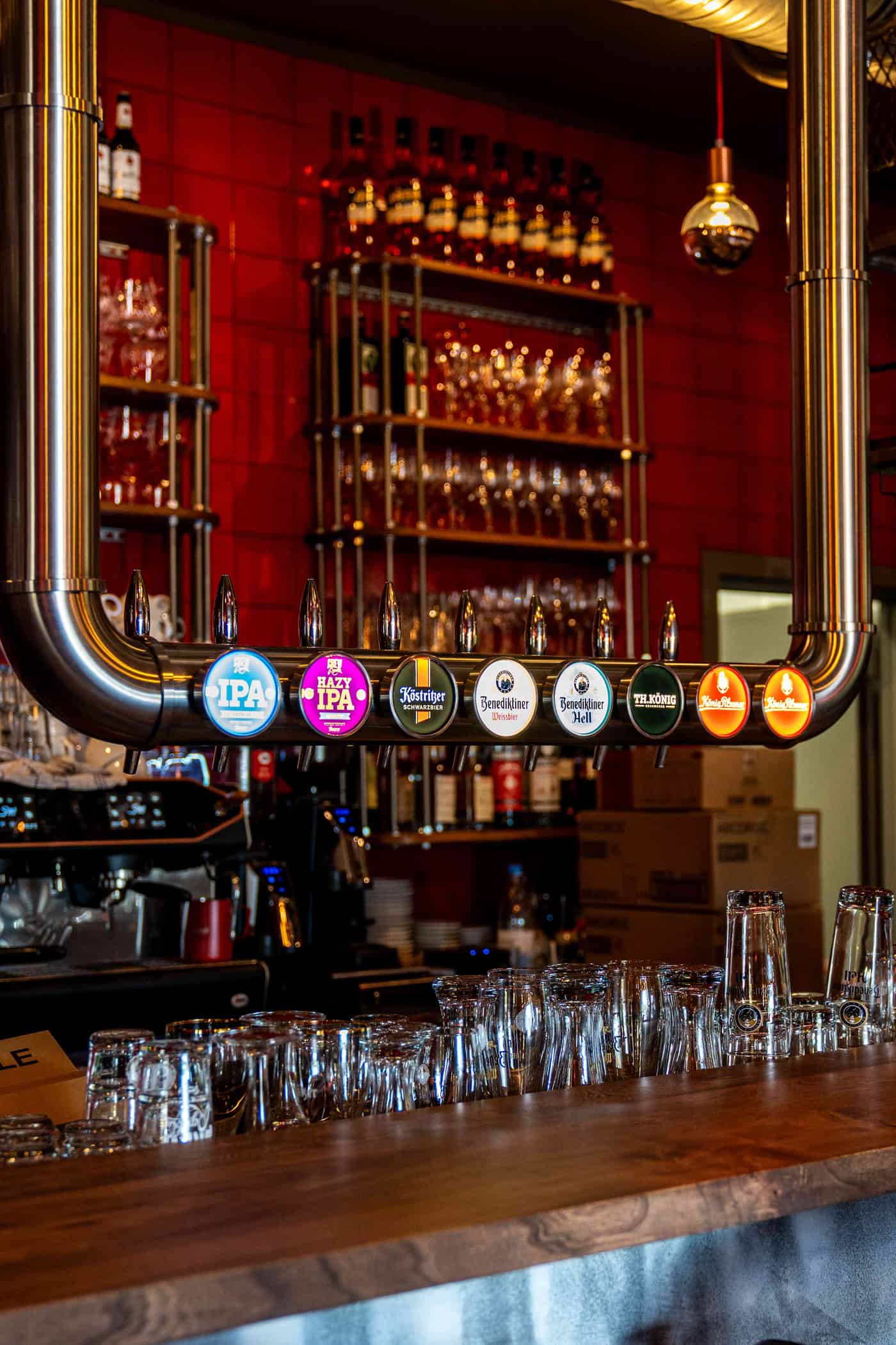 Zapfanlage im Wirtshaus Moers mit beleuchteten Biersorten wie IPA, Köstritzer, Benediktiner und König Pilsener vor roter Fliesenwand