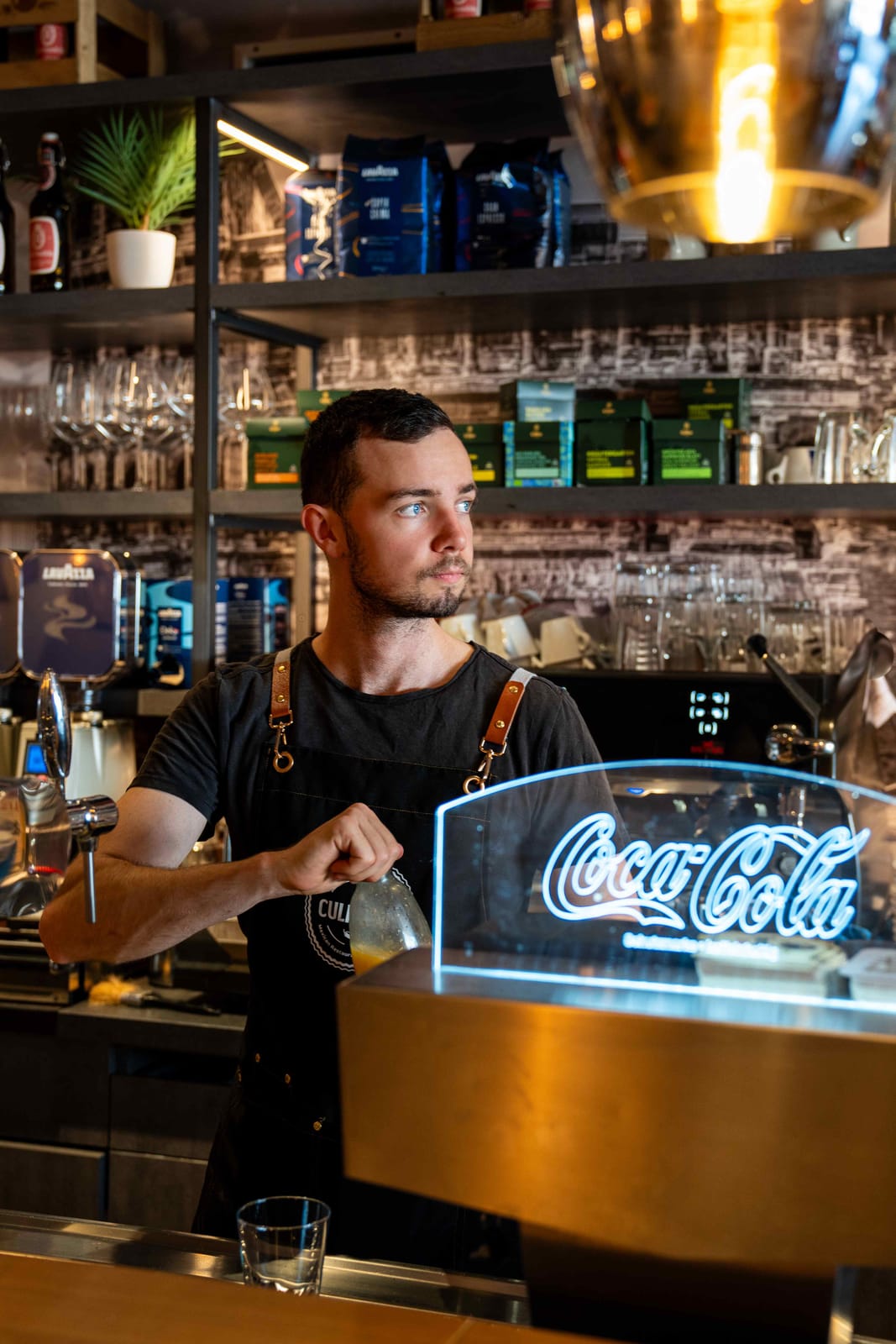 Barkeeper an der Theke eines Restaurants mit Coca-Cola-Leuchtschild