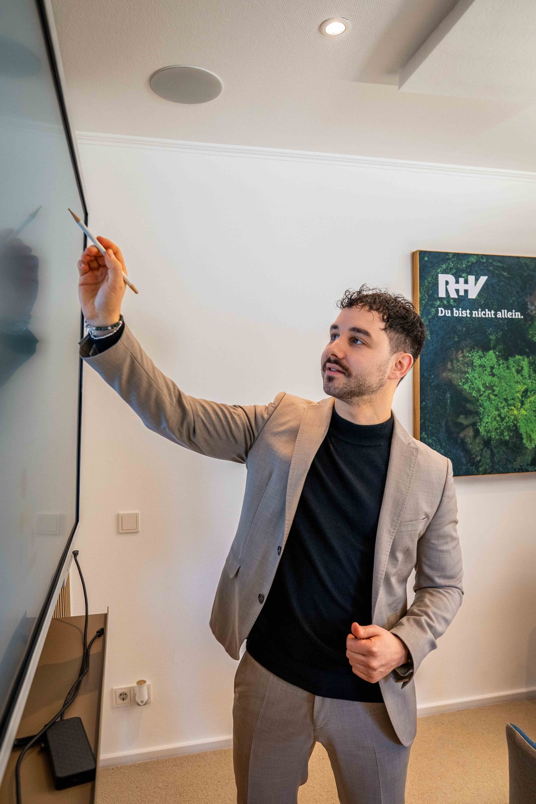 Berater präsentiert an einem Bildschirm im Büro der R+V Versicherung